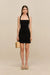 Woman wearing a black knit mini dress with a halter neck and square neckline. 