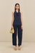 Woman wearing navy utility style barrel leg pants that hit at the ankle, paired with a blue top and tan sandals. 