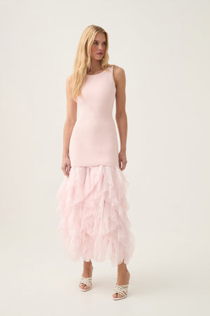 Woman wears pink bodycon maxi dress with ruffle hem.