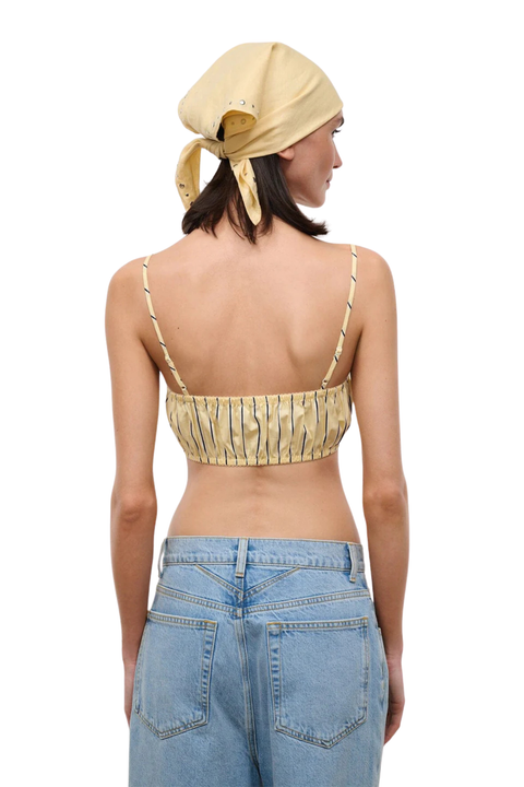 Woman wearing a striped yellow crop top on a white background back angle