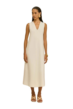 Woman wearing a white sleeveless dress against a beige background
