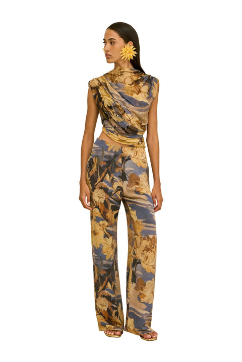 Woman wearing a floral jumpsuit on a beige background.