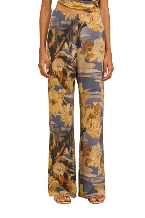 Detail shot of woman wearing a floral jumpsuit on a beige background.