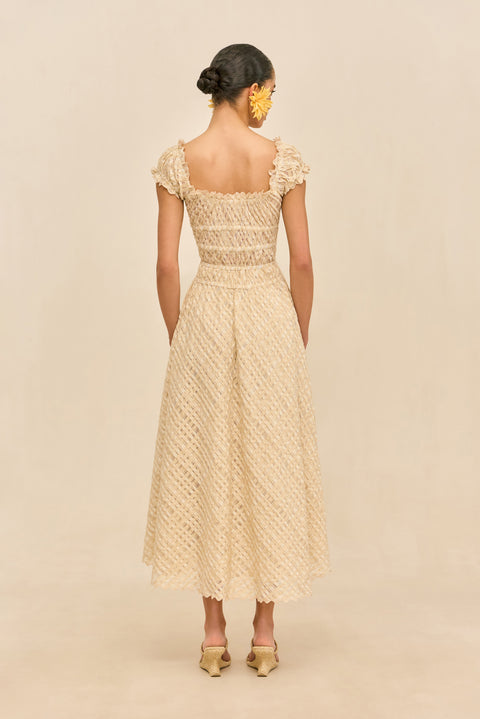 Back-facing woman wearing a woven beige dress with buttons against a beige background.