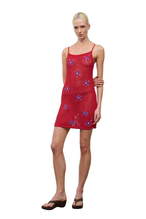 Woman wearing a red dress with floral patterns on a white background
