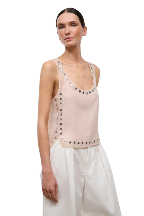 A woman wearing a pink sheer organza sleeveless top with stud embellishments