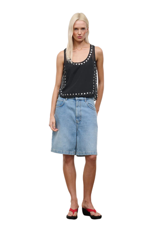 A woman wearing a black sheer organza sleeveless top with stud embellishments