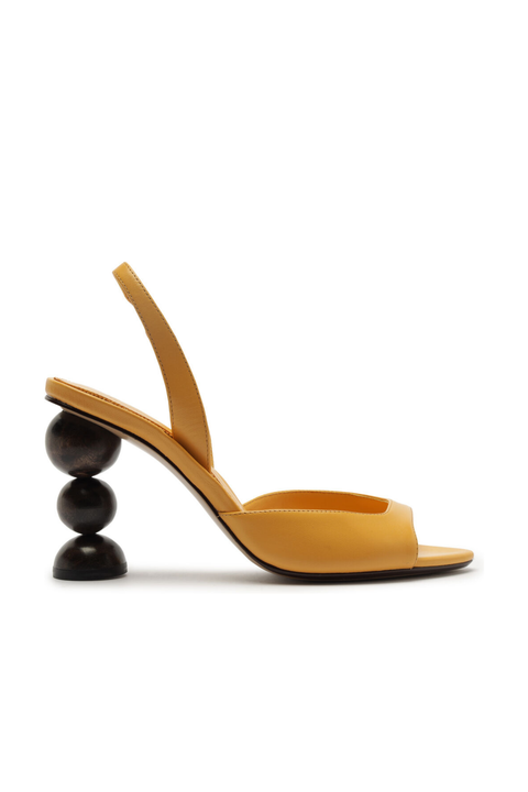 Mustard yellow sandal with a unique sphered black heel design on a white background