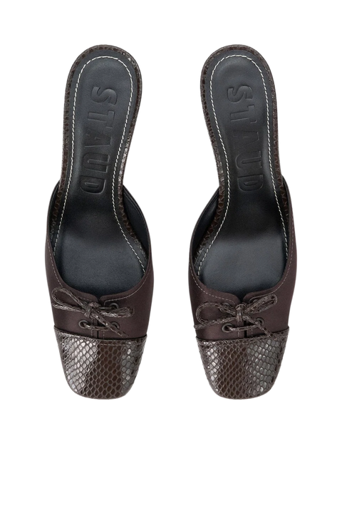 A pair of dark brown mule sandals with a textured snakeskin-patterned toe cap and matching bow detail on the vamp, shown from a top-down view on a white background.