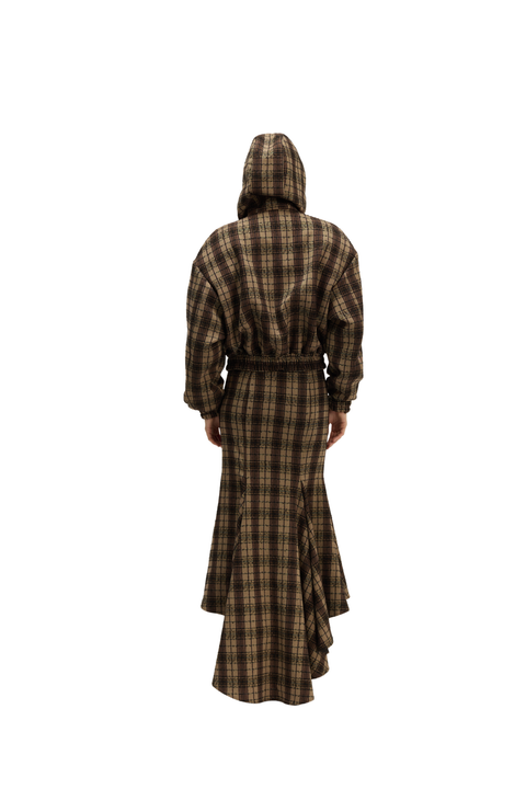 A person viewed from the back wearing a long hooded robe or dress in a brown and tan plaid pattern, standing against a plain white background.