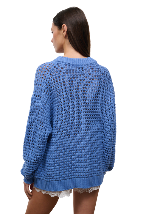 A woman shown from the back wearing a blue open-knit crewneck sweater, photographed against a plain white background.