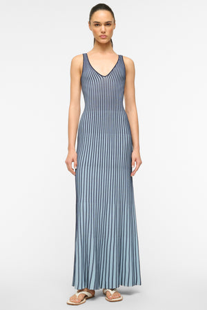 Woman wearing a two-toned navy and light blue knit pleated maxi dress that features a deep-v. 