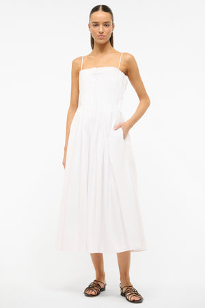 Model with hand in pocket of the white pleated midi bella dress.