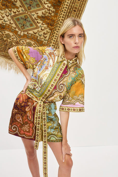 Close up of a woman posing and wearing a multicolor, printed, mini shirtdress that features a point collar and self-tie belt. 