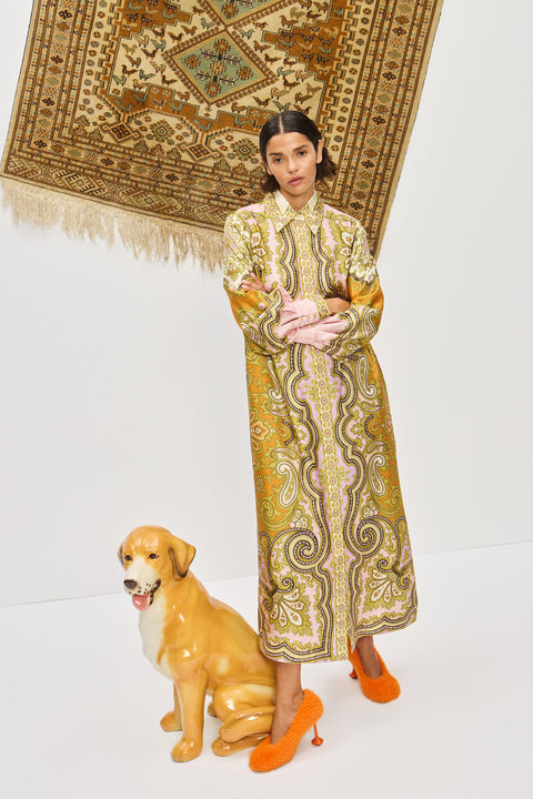Woman wearing a multicolor, midi length, long sleeve shirt dress that features a point collar, balloon sleeves, and a self tie belt, paired with orange heels. 