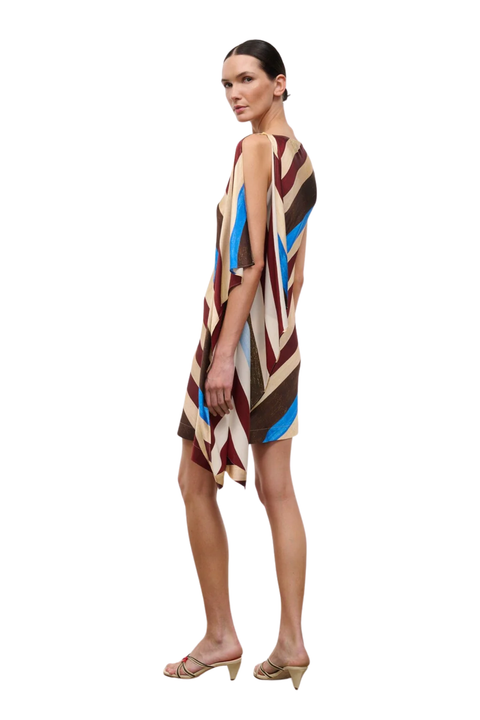 A woman modeling a sleeveless, knee-length dress with a bold striped pattern in brown, beige, blue, and burgundy, paired with beige heeled sandals against a plain white background.