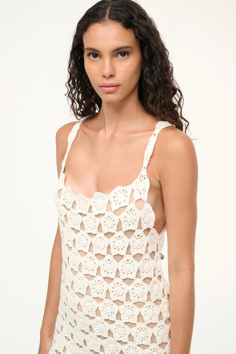 Close up of a woman wearing a white floral crochet mini tank dress that features a nude lining.
