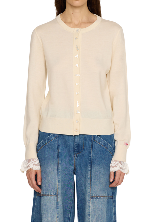 A model wearing a cream-colored long-sleeve knit cardigan with lace ruffle cuffs and a button-up front, paired with blue denim jeans against a plain white background.