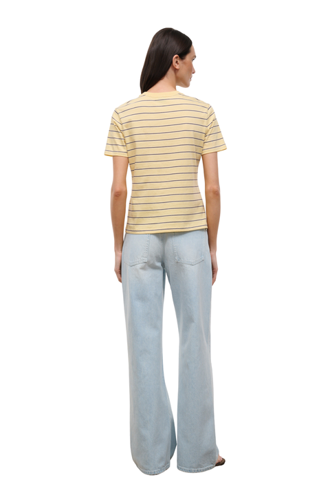 A woman shown from the back wearing a short-sleeve crewneck t-shirt with thin yellow horizontal stripes on a cream base, paired with light-wash wide-leg jeans, against a plain white background.