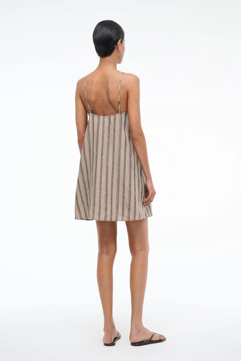 Back view of a woman wearing a spaghetti strap, mini shift dress that is crafted from a brown stripe linen. 