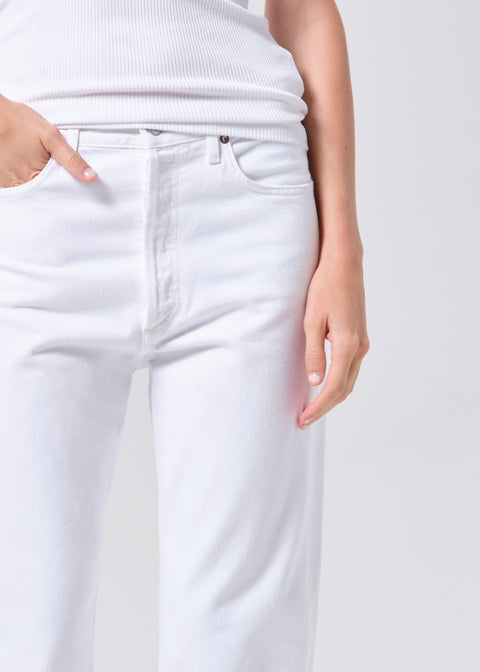 Person wearing a white sleeveless top and high-rise, straight leg, white jeans on a plain background zoomed in 