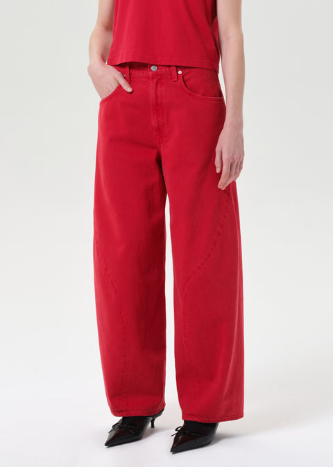 Person turned wearing red wide-leg jeans and a red top on a white background