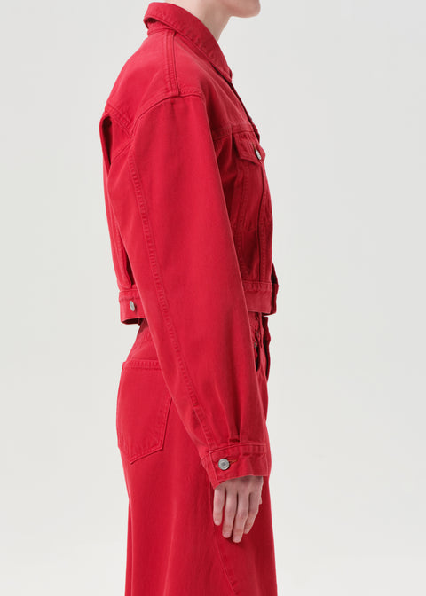 Side view of red denim jacket and jeans worn by a person on a light gray background