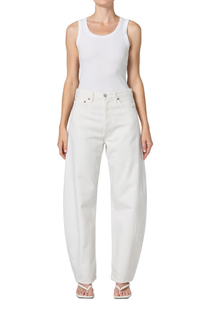 Person wearing white mid-rise jeans and a white tank top on a white background facing forward