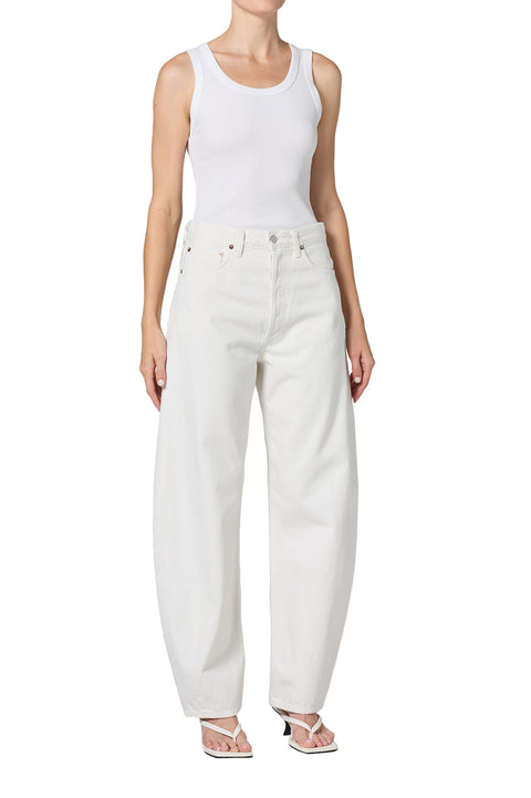 Person wearing white mid-rise jeans and a white tank top on a white background off-center view 