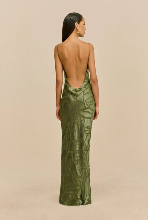 Back-facing shot of woman wearing a green evening gown against a beige background