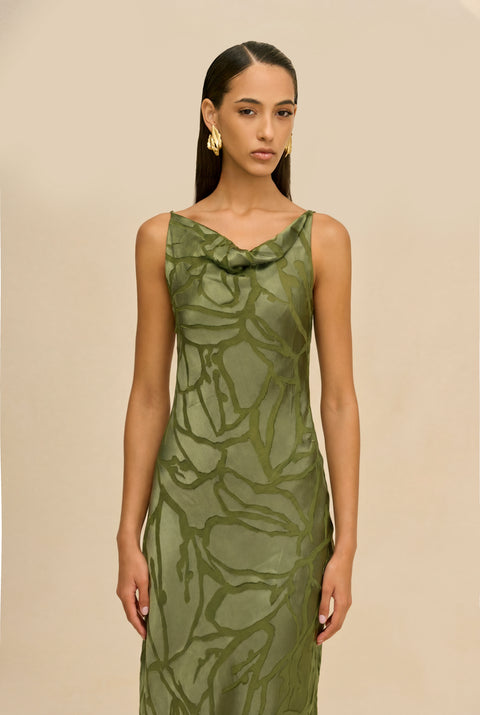 Detail shot of woman wearing a green evening gown against a beige background