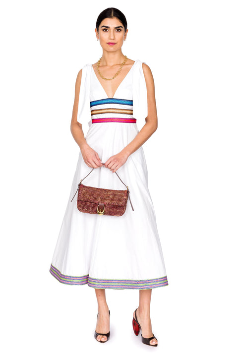 Model styled in white cotton dress with raffia ribbons and brown handbag.