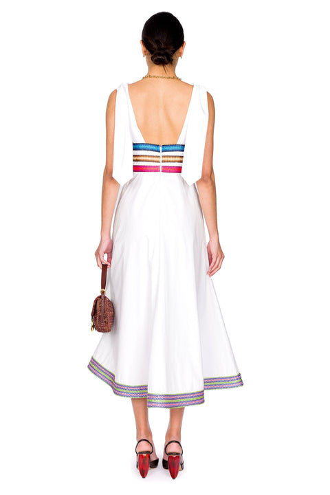 Model shows back of white midi dress with raffia  ribbon details.