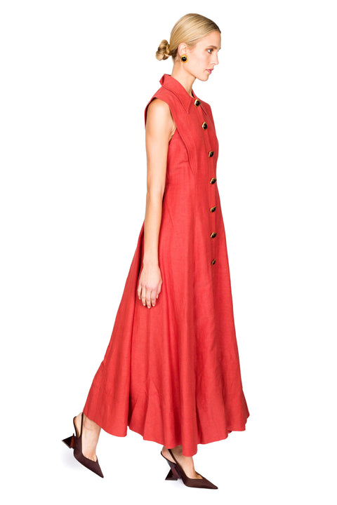 Woman walking to the right wearing a red sleeveless collared maxi dress with buttons on a white background from the side