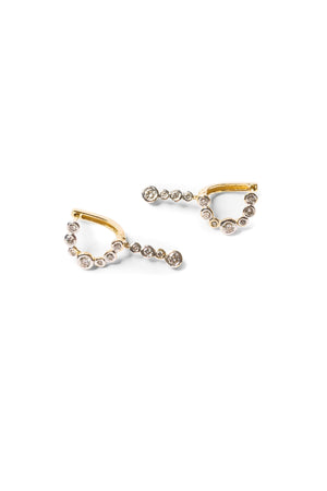 Pair of gold diamond earrings that features a C-shaped line of round diamonds set in white gold bezels. 
