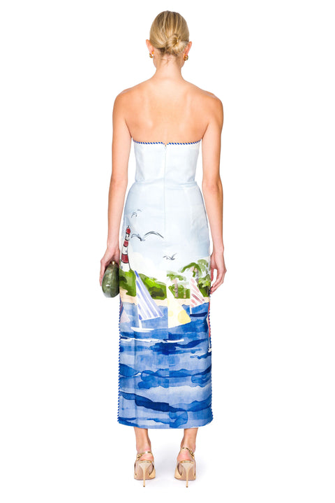 Woman showing back of a maxi strapless dress with a scenic sailboat  print on a white background