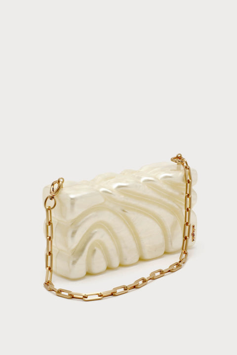 Textured pearlescent clutch with ornate design with chain strap facing downward.