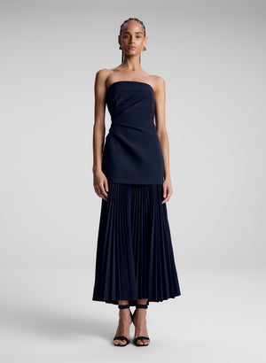 Model wearing navy blue strapless maxi dress with pleats.