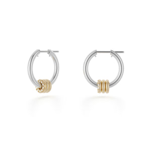 Ghost image of a pair of Spinelli Kilcollin Ara earrings that feature a mini sterling silver hoop adorned by three 18k yellow gold annulets, with the foremost one pave with white diamonds. 