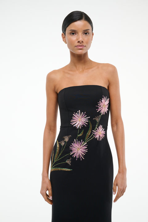 Close up of a woman wearing black, strapless midi dress that features pink dahlia embellishments across the bodice. 