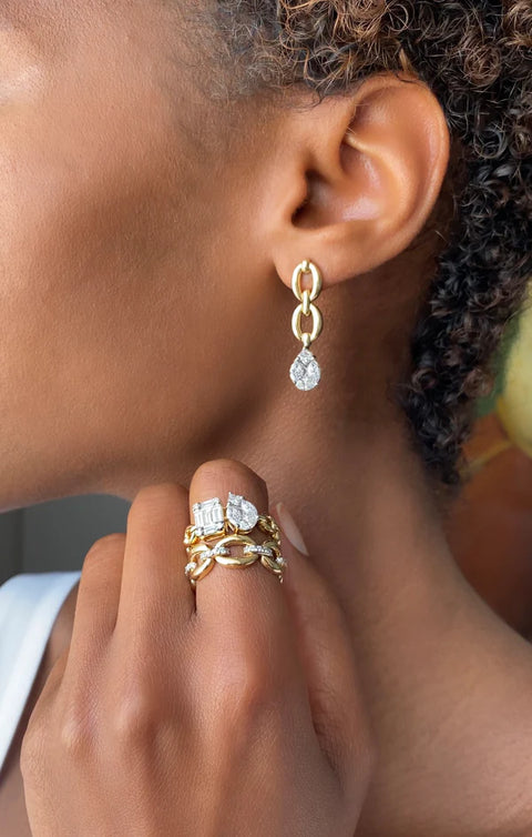 A woman wearing a yellow gold chain ring that features an illusion emerald cut diamond and an illusion pear diamond. 