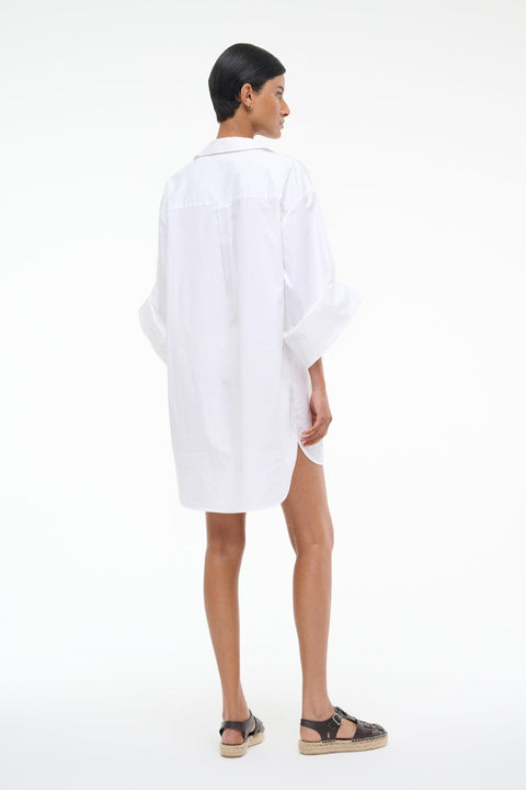 Back-facing person wearing a white shirt dress on a white background