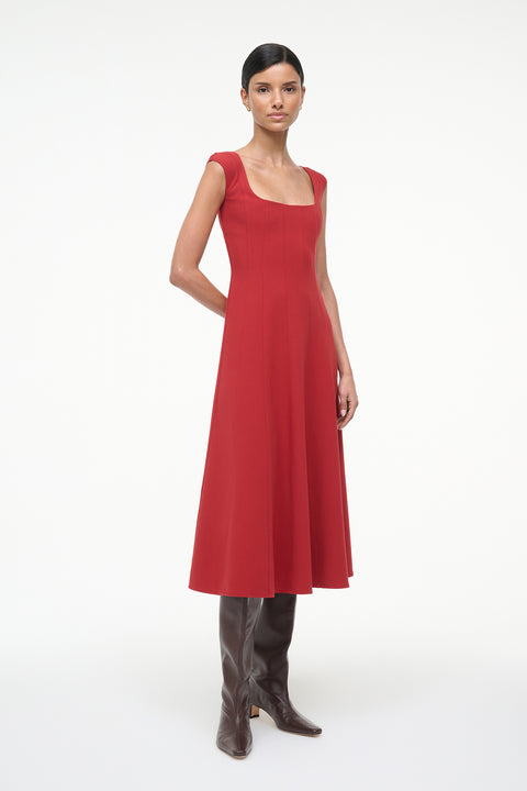 Side-facing woman wearing a red sleeveless midi dress with boots. 