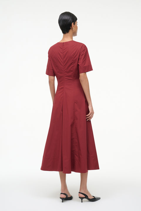 Back-facing woman wearing a red midi dress on a white background