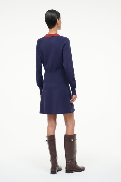 Person wearing a navy dress and brown boots on a white background