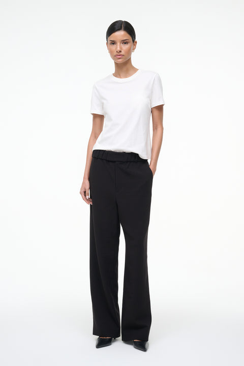 Person wearing a white t-shirt and black pants on a white background