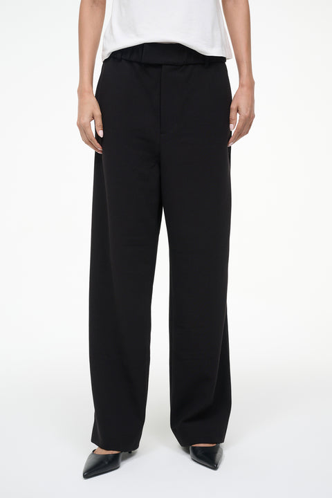 Person wearing black wide-leg pants and a white top on a white background