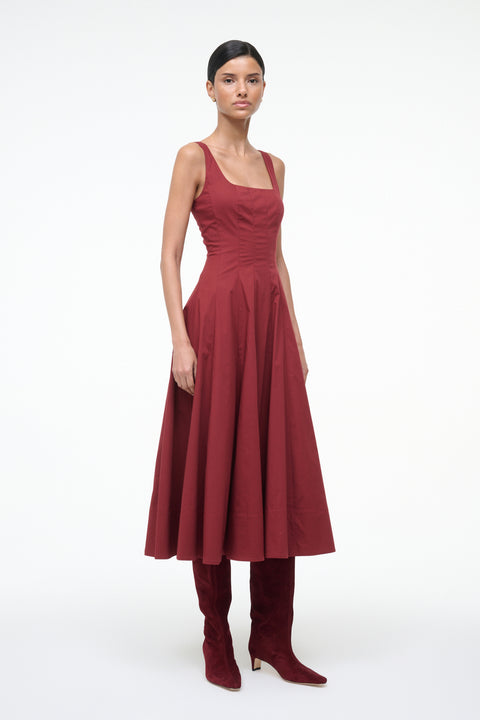 Woman wearing a red dress with matching boots on a white background