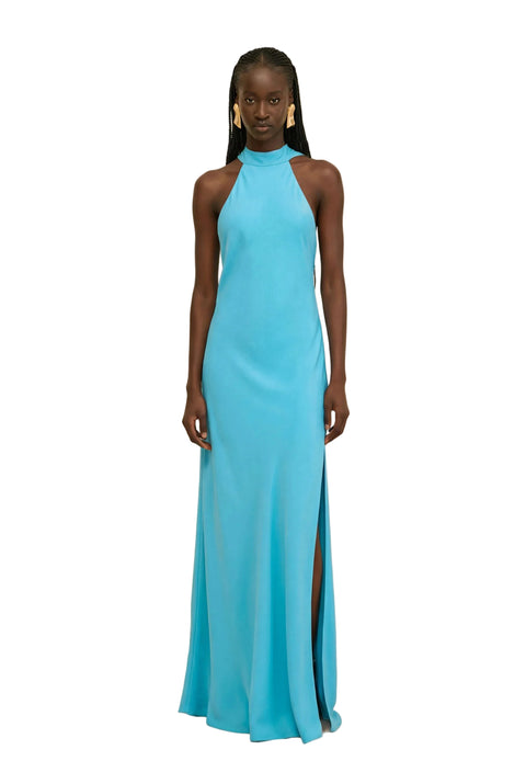 Woman wearing a blue halter neck gown on a beige background.