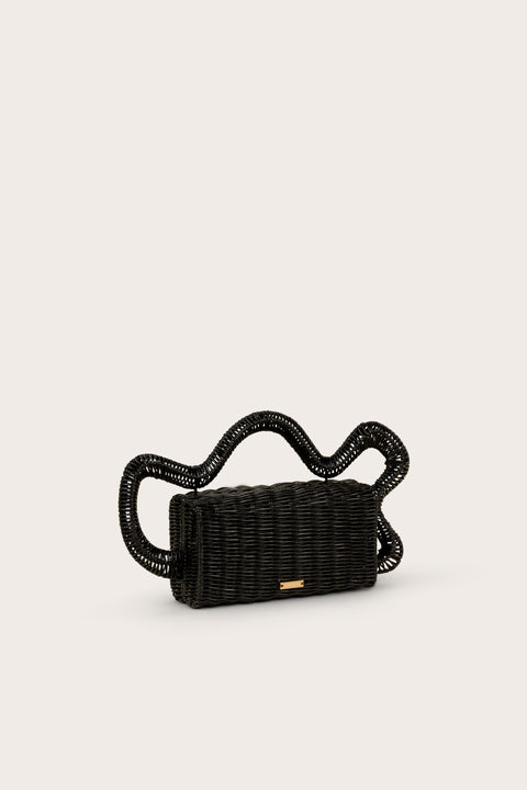 Side view of a black, rectangular rattan clutch that features an abstract wave top handle. 